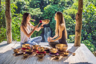 Spa salonunda Nepal Buda bakır kasesi. Genç, güzel bir kadın masaj terapisi yapıyor. Spa 'da şelaleye karşı kâseler söylüyor. Ses terapisi, dinlenme, meditasyon, sağlıklı yaşam tarzı ve...