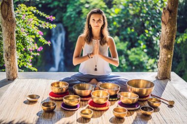 Tibet'te bir şelaleye karşı yoga minderinde otururken çalan kadın. Vintage tonlu. Mala boncuk meditasyon ile güzel kız