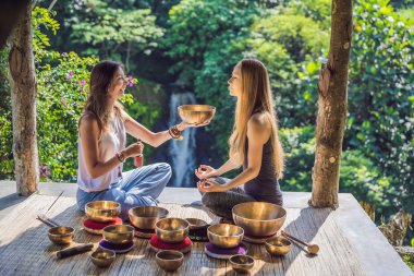 Spa salonunda Nepal Buda bakır kasesi. Genç, güzel bir kadın masaj terapisi yapıyor. Spa 'da şelaleye karşı kâseler söylüyor. Ses terapisi, dinlenme, meditasyon, sağlıklı yaşam tarzı ve...