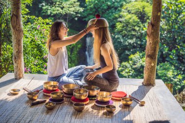 Spa salonunda Nepal Buda bakır kasesi. Genç, güzel bir kadın masaj terapisi yapıyor. Spa 'da şelaleye karşı kâseler söylüyor. Ses terapisi, dinlenme, meditasyon, sağlıklı yaşam tarzı ve...