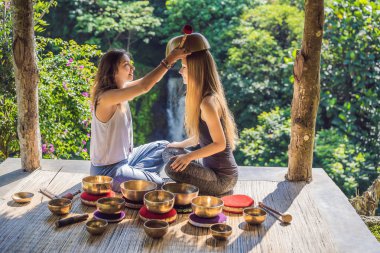 Spa salonunda Nepal Buda bakır kasesi. Genç, güzel bir kadın masaj terapisi yapıyor. Spa 'da şelaleye karşı kâseler söylüyor. Ses terapisi, dinlenme, meditasyon, sağlıklı yaşam tarzı ve...