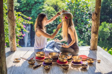 Spa salonunda Nepal Buda bakır kasesi. Genç, güzel bir kadın masaj terapisi yapıyor. Spa 'da şelaleye karşı kâseler söylüyor. Ses terapisi, dinlenme, meditasyon, sağlıklı yaşam tarzı ve...