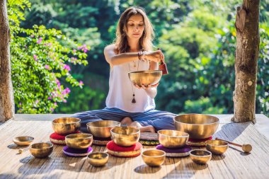 Tibet'te bir şelaleye karşı yoga minderinde otururken çalan kadın. Vintage tonlu. Mala boncuk meditasyon ile güzel kız