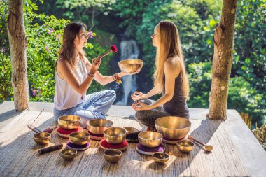 Spa salonunda Nepal Buda bakır kasesi. Genç, güzel bir kadın masaj terapisi yapıyor. Spa 'da şelaleye karşı kâseler söylüyor. Ses terapisi, dinlenme, meditasyon, sağlıklı yaşam tarzı ve...