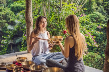 Spa salonunda Nepal Buda bakır kasesi. Genç, güzel bir kadın masaj terapisi yapıyor. Spa 'da şelaleye karşı kâseler söylüyor. Ses terapisi, dinlenme, meditasyon, sağlıklı yaşam tarzı ve...