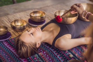 Spa salonunda Nepal Buda bakır kasesi. Genç, güzel bir kadın masaj terapisi yapıyor. Spa 'da şelaleye karşı kâseler söylüyor. Ses terapisi, dinlenme, meditasyon, sağlıklı yaşam tarzı ve...