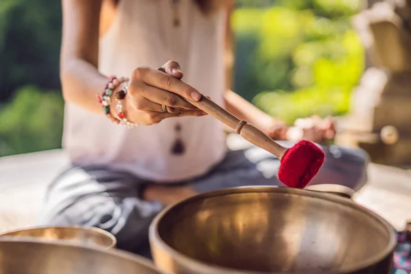 Nepal Buda tigela de cobre cantando no salão de spa. Jovem mulher bonita fazendo massagem terapia cantando tigelas no Spa contra uma cachoeira. Terapia sonora, recreação, meditação, estilo de vida saudável e — Fotografia de Stock