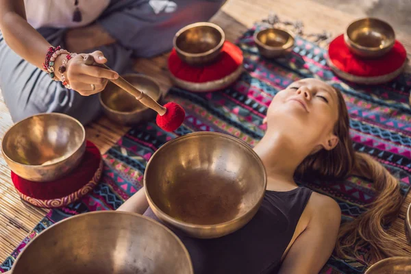 Nepal Budda ciotola di rame canto al salone spa. Giovane bella donna che fa terapia di massaggio cantando ciotole nella Spa contro una cascata. Terapia del suono, ricreazione, meditazione, stile di vita sano e — Foto Stock