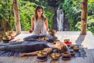 Spa salonunda Nepal Buda bakır kasesi. Genç, güzel bir kadın masaj terapisi yapıyor. Spa 'da şelaleye karşı kâseler söylüyor. Ses terapisi, dinlenme, meditasyon, sağlıklı yaşam tarzı ve...