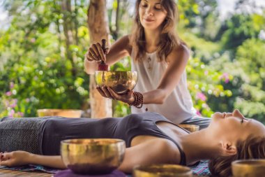 Spa salonunda Nepal Buda bakır kasesi. Genç, güzel bir kadın masaj terapisi yapıyor. Spa 'da şelaleye karşı kâseler söylüyor. Ses terapisi, dinlenme, meditasyon, sağlıklı yaşam tarzı ve...