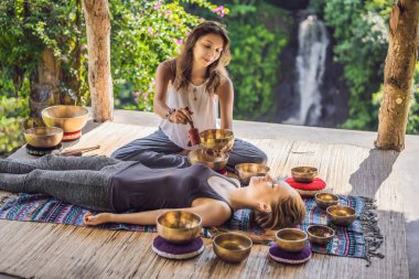 Spa salonunda Nepal Buda bakır kasesi. Genç, güzel bir kadın masaj terapisi yapıyor. Spa 'da şelaleye karşı kâseler söylüyor. Ses terapisi, dinlenme, meditasyon, sağlıklı yaşam tarzı ve...