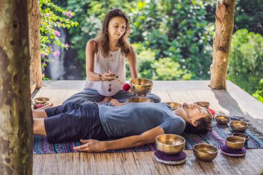Spa salonunda Nepal Buda bakır şarkı kase. Genç güzel adam bir şelale karşı Spa'da şarkı kase masaj terapisi yapıyor. Ses terapisi, rekreasyon, meditasyon, sağlıklı yaşam tarzı ve vücut