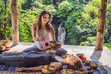 Spa salonunda Nepal Buda bakır kasesi. Genç, güzel bir kadın masaj terapisi yapıyor. Spa 'da şelaleye karşı kâseler söylüyor. Ses terapisi, dinlenme, meditasyon, sağlıklı yaşam tarzı ve...