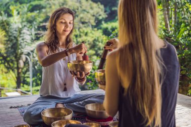 Spa salonunda Nepal Buda bakır kasesi. Genç, güzel bir kadın masaj terapisi yapıyor. Spa 'da şelaleye karşı kâseler söylüyor. Ses terapisi, dinlenme, meditasyon, sağlıklı yaşam tarzı ve...