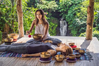 Spa salonunda Nepal Buda bakır kasesi. Genç, güzel bir kadın masaj terapisi yapıyor. Spa 'da şelaleye karşı kâseler söylüyor. Ses terapisi, dinlenme, meditasyon, sağlıklı yaşam tarzı ve...