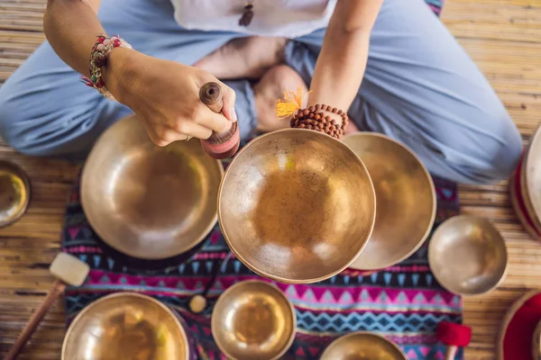 Vrouw spelen op Tibetaanse Singing Bowl terwijl zittend op yoga mat tegen een waterval. Vintage tonned. Mooi meisje met Mala kralen mediteren — Stockfoto