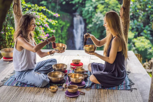 Spa salonunda Nepal Buda bakır kasesi. Genç, güzel bir kadın masaj terapisi yapıyor. Spa 'da şelaleye karşı kâseler söylüyor. Ses terapisi, dinlenme, meditasyon, sağlıklı yaşam tarzı ve...