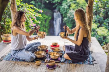Spa salonunda Nepal Buda bakır kasesi. Genç, güzel bir kadın masaj terapisi yapıyor. Spa 'da şelaleye karşı kâseler söylüyor. Ses terapisi, dinlenme, meditasyon, sağlıklı yaşam tarzı ve...