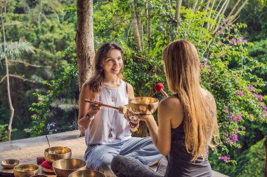 Spa salonunda Nepal Buda bakır kasesi. Genç, güzel bir kadın masaj terapisi yapıyor. Spa 'da şelaleye karşı kâseler söylüyor. Ses terapisi, dinlenme, meditasyon, sağlıklı yaşam tarzı ve...