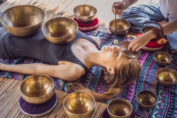 Nepal Buda tigela de cobre cantando no salão de spa. Jovem mulher bonita fazendo massagem terapia cantando tigelas no Spa contra uma cachoeira. Terapia sonora, recreação, meditação, estilo de vida saudável e — Fotografia de Stock