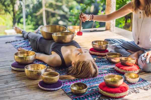 Nepal Budda ciotola di rame canto al salone spa. Giovane bella donna che fa terapia di massaggio cantando ciotole nella Spa contro una cascata. Terapia del suono, ricreazione, meditazione, stile di vita sano e — Foto Stock