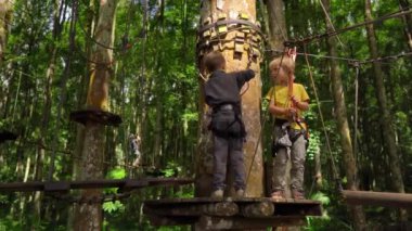 Bir güvenlik koşum iki küçük çocuk bir orman macera parkı bir rota üzerinde tırmanmaya. Yüksek halat patikalarına tırmanıyorlar. Zip hatları ve her türlü oluşan tırmanma faaliyetleri ile açık eğlence merkezi