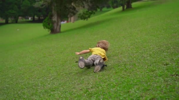 Superslowmotion tiro de dois meninos se divertir em um gramado. Eles rolam pela colina abaixo — Vídeo de Stock