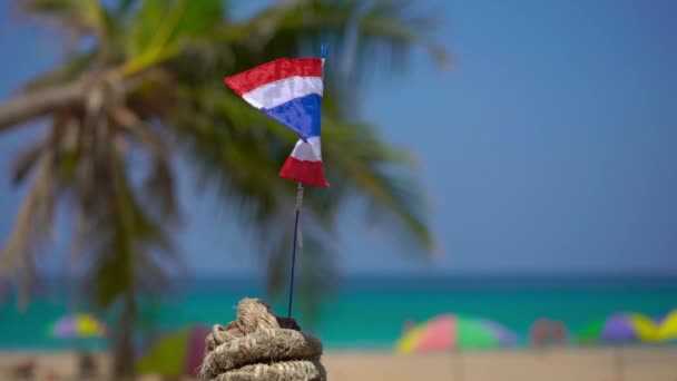 Superslowmotion skott av en nationell flagga av Thailand på en vacker strand. Tropiskt semesterkoncept. Resa till Thailand Concept — Stockvideo