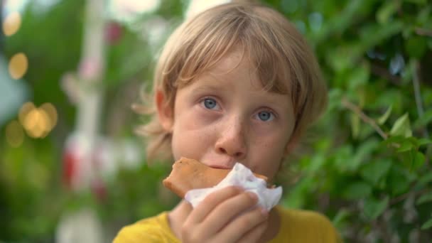 Primer plano de un niño comiendo un delicioso panqueque en un mercado callejero. Concepto de comida callejera . — Vídeos de Stock