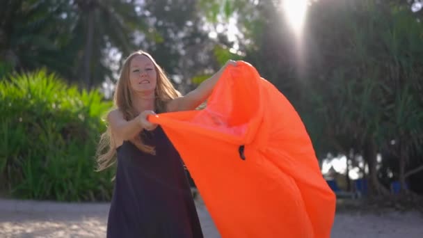 Superslowmotion tiro de una mujer joven en una playa tropical inflando un sofá inflable. Concepto vacaciones de verano — Vídeo de stock