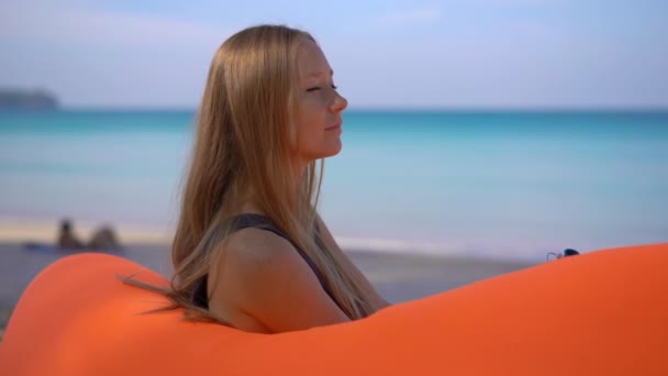 Fotografía en cámara lenta de una joven en una playa tropical sentada en un sofá inflable. Concepto vacaciones de verano — Vídeos de Stock