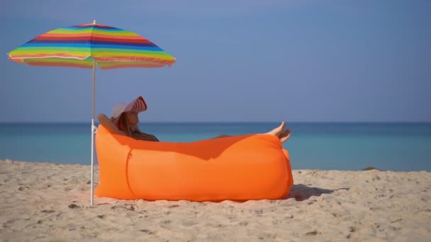 Superslowmotion shot van een jonge vrouw op een tropisch strand op een opblaasbare bank. Zomer vakantie concept — Stockvideo