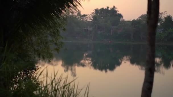 Slowmotion Point of View geschoten van een prachtige tropische weg met palmbomen en een meer achter de bomen tijdens zonsondergang. Reis in het tropen concept. Holidays concept — Stockvideo