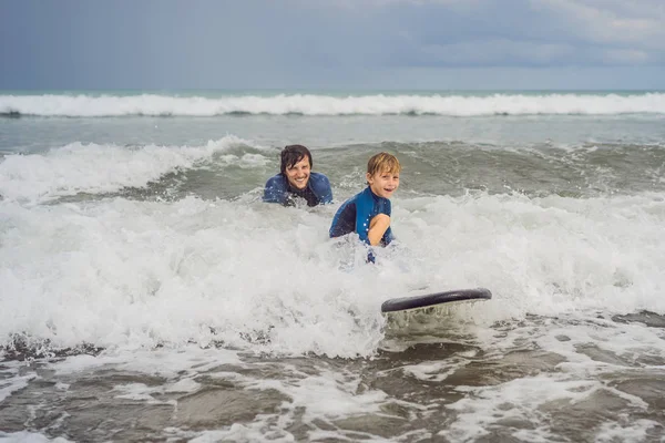 父やインストラクターは、休暇や休日に海でサーフィンする方法を彼の5歳の息子を教えています。子供のコンセプトを持つ旅行やスポーツ。子供のためのサーフィンレッスン — ストック写真