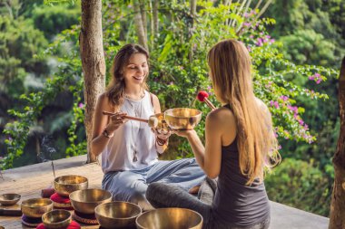 Spa salonunda Nepal Buda bakır kasesi. Genç, güzel bir kadın masaj terapisi yapıyor. Spa 'da şelaleye karşı kâseler söylüyor. Ses terapisi, dinlenme, meditasyon, sağlıklı yaşam tarzı ve...