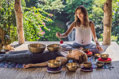 Spa salonunda Nepal Buda bakır kasesi. Genç, güzel bir kadın masaj terapisi yapıyor. Spa 'da şelaleye karşı kâseler söylüyor. Ses terapisi, dinlenme, meditasyon, sağlıklı yaşam tarzı ve...