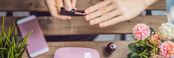 Jonge vrouw maakt manicure met gel Polish en UV lamp in roze tinten banner, lang formaat — Stockfoto