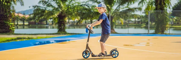 BANNER, LONGO FORMATO Criança feliz em chutar scooter na quadra de basquete. As crianças aprendem a andar de skate. Menino patinando no dia ensolarado de verão. Atividades ao ar livre para crianças em residências seguras — Fotografia de Stock