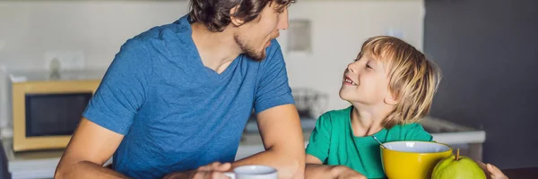 Padre e figlio stanno parlando e sorridendo mentre fanno colazione in cucina BANNER, FORMATO LUNGO — Foto Stock