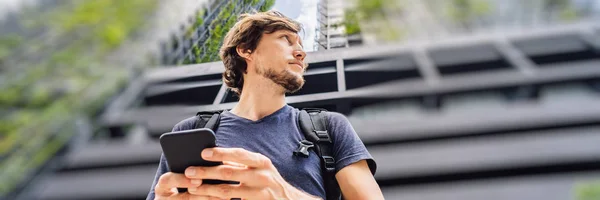Людина використовує додаток карти на смартфоні на фоні хмарочосів BANNER, LONG FORMAT — стокове фото