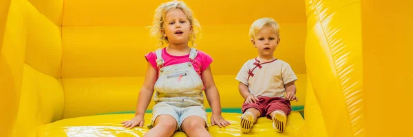 A boy and a girl ride from an inflatable slide BANNER, LONG FORMAT — Stock Photo, Image