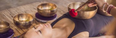 Banner, Uzun Format Nepal Buda bakır spa salonunda kase şarkı kase. Genç güzel kadın bir şelale karşı Spa'da şarkı kase masaj terapisi yapıyor. Ses terapisi, rekreasyon, meditasyon