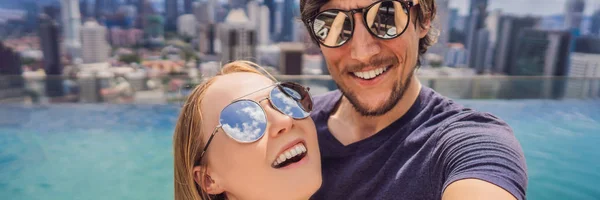 BANNER, FORMATO LUNGO giovane coppia felice e attraente giocoso scattare foto selfie insieme al lussuoso hotel urbano piscina a sfioro e vista panoramica della città godendo vacanze luna di miele viaggiare in — Foto Stock