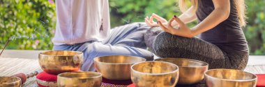 Banner, Uzun Format Nepal Buda bakır spa salonunda kase şarkı kase. Genç güzel kadın bir şelale karşı Spa'da şarkı kase masaj terapisi yapıyor. Ses terapisi, rekreasyon, meditasyon