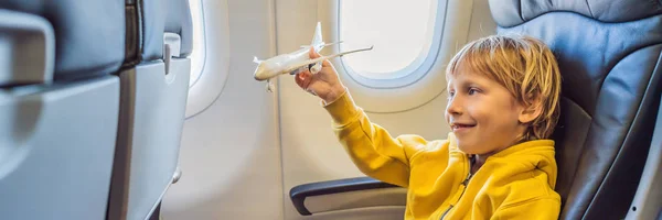 小さな男の子は休暇バナー、ロングフォーマットで飛ぶ民間ジェット機でおもちゃの飛行機で遊びます — ストック写真