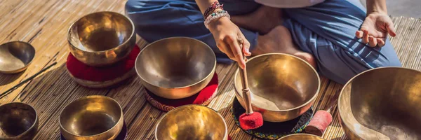 Vrouw spelen op Tibetaanse Singing Bowl terwijl zittend op yoga mat tegen een waterval. Vintage tonned. Mooi meisje met Mala kralen mediteren banner, lang formaat — Stockfoto