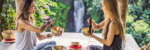 BANNER, LONG FORMAT Nepal Buddha copper singing bowl at spa salon. Young beautiful woman doing massage therapy singing bowls in the Spa against a waterfall. Sound therapy, recreation, meditation