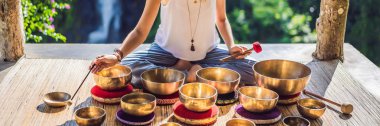 Tibet'te bir şelaleye karşı yoga minderinde otururken çalan kadın. Vintage tonlu. Mala boncuklu güzel kız Banner meditasyon, Uzun Format