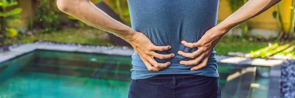 Mens back hurts against the backdrop of the pool. Pool helps with back pain BANNER, LONG FORMAT