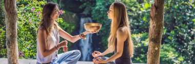 Banner, Uzun Format Nepal Buda bakır spa salonunda kase şarkı kase. Genç güzel kadın bir şelale karşı Spa'da şarkı kase masaj terapisi yapıyor. Ses terapisi, rekreasyon, meditasyon